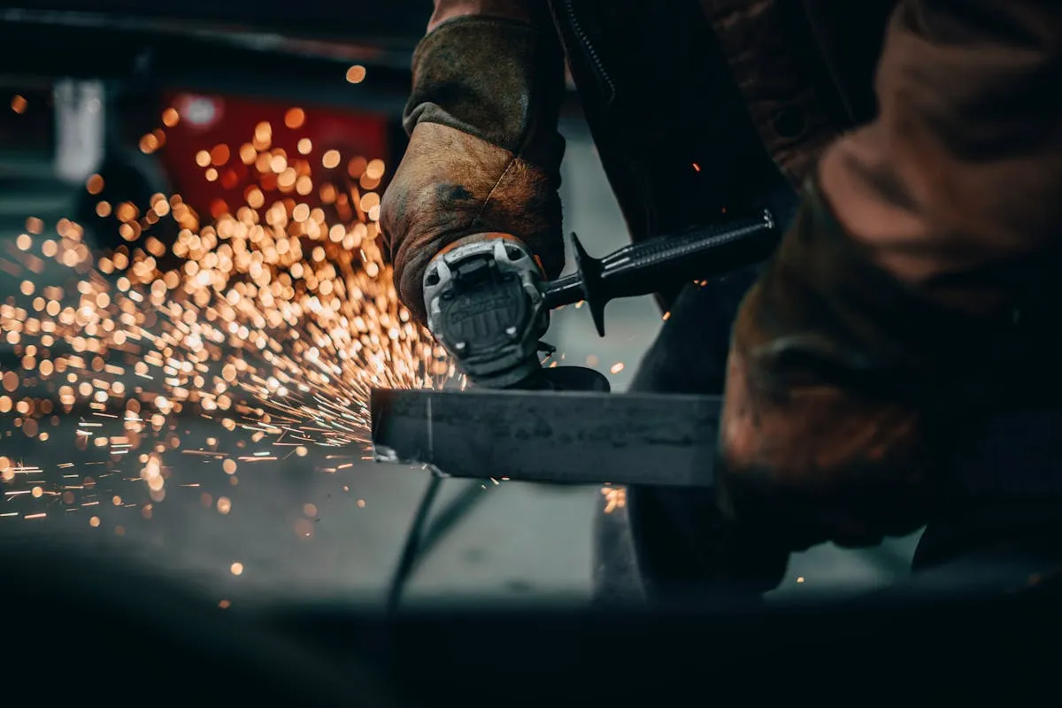 Metallbaumanufaktur - Schleifen von Metallteilen in der Werkshalle, Nahaufnahme.